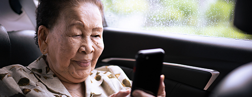 Image of a senior woman sitting in her car seat and looking at her phone